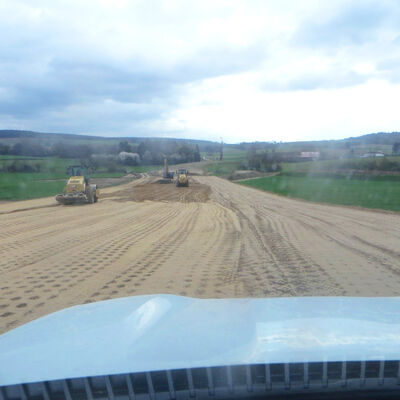Bild vergr&ouml;&szlig;ern: Der Weitblick über ein Baufeld zeigt drei Baufahrzeuge, die den Erdboden bearbeiten