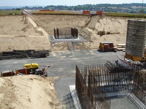 Rechts und links eines geschotterten Wegs sieht man jeweils ein betoniertes Fundament, aus dem Metallsäbe hinaus ragen