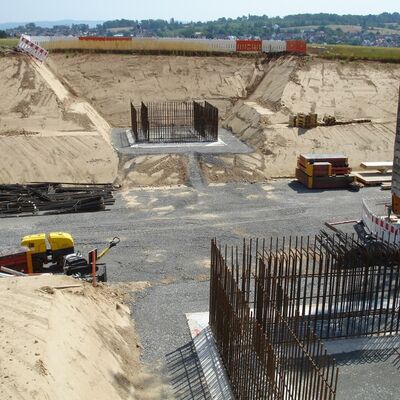 Bild vergr&ouml;&szlig;ern: Rechts und links eines geschotterten Wegs sieht man jeweils ein betoniertes Fundament, aus dem Metallsäbe hinaus ragen
