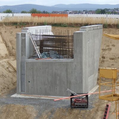 Bild vergr&ouml;&szlig;ern: Würfelförmig ragt Beton aus hellbrauner Erde