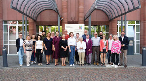 21 Personen, neben einander aufgestellt in zwei Reihen, posieren gemeinsam für das Foto; ganz rechts Landrat Dr. Alexander Legler